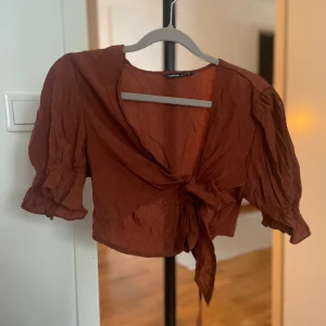 Bolero blus med knytband rostfärgad - Rostfärgad bolero eller blus med volanger i ärmarna. Man knyter den vid brösten.