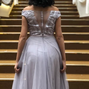 lilasilvrig festlig långklänning  - En jättefin lilasilvrig klänning med otroligt eleganta detaljer i storlek 36. Har använts en gång men letar nu ny ägare då den har blivit för liten på mig.  Den når ner till marken för mig när jag har på mig 3 cm klackar (jag är 170cm). 