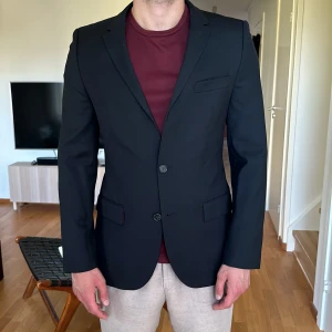 Kavaj Hugo Boss str 48 svart - Kavaj från Hugo Boss Storlek: 48 Färg: svart  En liten skada på vänster arm, knappt synlig. I övrigt i mycket gott skick 