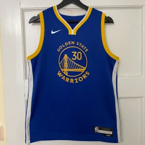 Stephen Curry Jersey - Jerseyn har storleken L, fast den passar bättre som M. Köptes på Plick för ett par veckor sedan fast säljer jerseyn nu då den nästan börjar bli för liten (182cm, 65kg).  Kontakta mig för fler bilder, om frågor eller om du är intresserad!