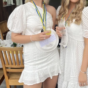 Klänning från NA-KD - Superfin vit broderad klänning från NA-KD, endast använd en gång på studenten men i väldigt bra skick då den bara användes på utspringet. Har dragkedja på sidan, och en underkjol😍