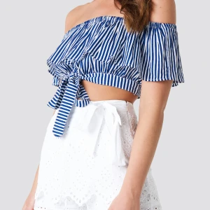 Off shoulder frill topp NAKD by  - The Off Shoulder Frill Top by Debiflue x NA-KD features an off shoulder, cropped design, and a self-tie detail.