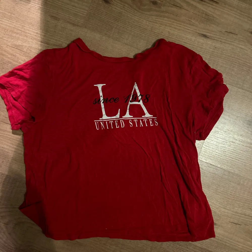 en röd t-shirt från H&M med tryck över framsidan. Tröjan är lite kortare över magen. Använd men i bra kvalite. Storlekalappen är borta, men är säker på att storleken är s, relativt i storlek M. 💗🤩💃. T-shirts.