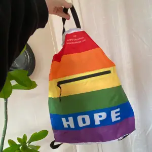Helt oanvänd väska från Hope limited edition för Pride. Ficka på utsidan med dragkedja. Helt oanvänd. 