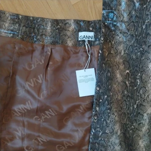 Midi skirt Ganni size 40 - Midi skirt Ganni with python effect print.   Wallet closure with bow  Composition: 53% Polyester, 47% Polyurethane