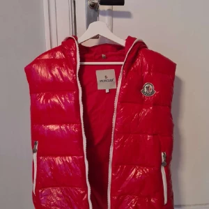 Moncler väst röd - En röd dunväst från Moncler! I bra skick, storlek S. Tveka inte att kontakta vid eventuella frågor :)