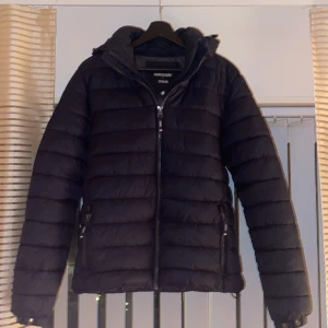 Superdry jacka - Jag säljer nu min väldigt snygga jacka från superdry. Den har väldigt snygga detaljer med silvriga knappar och dragkedja och är i en snygg mörkblå färg. Den är i väldigt bra skick och har inga hål eller liknande. Peis kan diskuteras vid snabb affär.