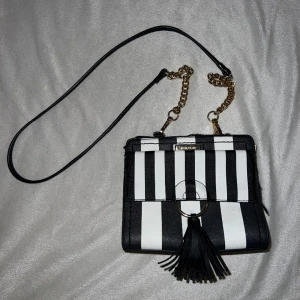 Randig handväska - Randig handväska med en tofs. Gulddetaljer. Beställd från Zalando.