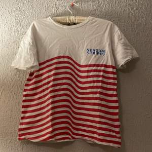  En fin t-shirt med röda bågiga streck på och blå text knappt använd 
