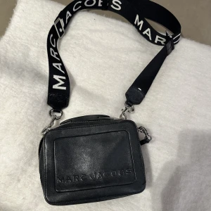 Marc Jacobs väska  - Säljer min fina väska från Marc Jacobs💘Väskan är sparsamt använd sedan 2019, inga skador eller likande. Den har två fack med dragkedja, silverdetaljer och ett separat köpt band med vita bokstäver. Köpte väskan för 5000kr, kvitto finns sparat! 💘👛