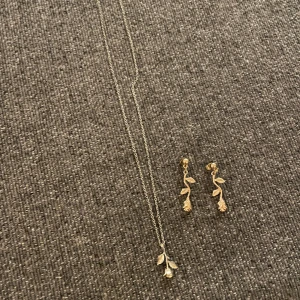 Set halsband o örhängen - Set med halsband o örhängen. Guldfärgat med hängande rosor