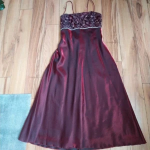 Balkläning - Vinröd balklänninge i storlek 34-38 (xs-s/m), pärlbroderad överdel. Den har en korsett baktill och matchande sjal. Otroligt fint skick, inga hål, fläckar osv. Köpt second hand men aldrig använt. 🎀 