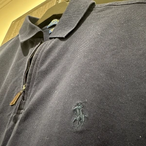 Ralph lauren, Half zip pike (marinblå) - En unik half zip pike av Ralph och lauren. Trendig och snygg och perfekt för bruk i varmt väder. Använd fåtal gånger, Cond: 9,5/10. Tveka inte vid funderingar, köparen står för frakten📦