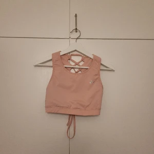 Träningstopp - En rosa träningstopp med knytning på ryggen. Endast använd enstaka gånger. Storlek M, men känns som XS/S