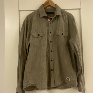 Ellos långärmad skjorta L - Ellos khakigrön långärmad skjorta i ”linnelook” stl L. Fint skick. Inga hål eller fläckar. 🌸 Vi tvättar parfymfritt, röker INTE men katt finns i hemmet sedan några veckor tillbaka.