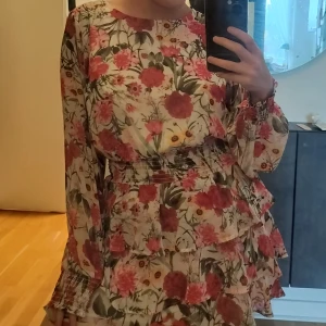 Rödblommig klänning med volanger - Superfin röd och blommig klänning med volanger nedtill. Storlek 36 eller 38, ska dubbelkolla 