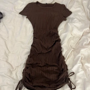 Brun klänning - Brun klänning med scrunch på sidan. Kan göras längre och kortare med hjälp av scrunchen på sidan