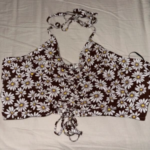 Topp - Brun topp med blommor man knyter den uppe ifrån i naken, har aldrig använt den dene helt ny.