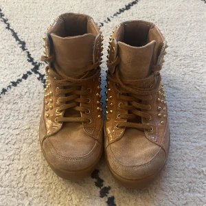 Skor med nitar från Kurt Geiger London - Höga sneakers i mocka och lack med guld nitar. Använt skick.