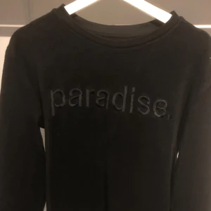 Svart tröja från Zara Man - En svart tröja från Zara Man med texten 'paradise' broderad på framsidan. Tröjan har långa ärmar och en rund halsringning.