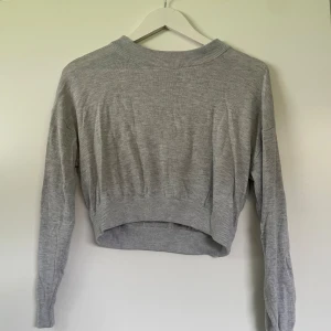 Grå stickad tröja - En superfin kort stickad tröja! Den är tunn i materialet så funkar bra även på sommaren! Sparsamt använd så är i utmärkt skick:)