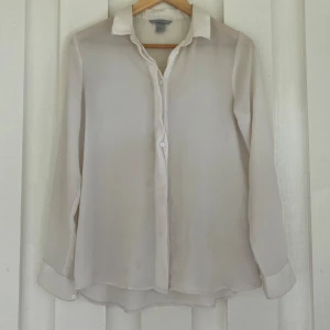 Vit skjorta från H&M - En fin, klassisk vit skjorta från h&m i satinliknande material. Den är väl använd med några små defekter men inget allt för märkbart :) skriv för fler bilder 