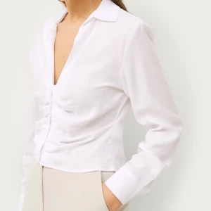 Vit långärmad skjorta - En elegant vit långärmad skjorta med knappar framtill. Väldigt luftig och skön, ganska tunn, anväbd typ 2 gånger så som ny. minns ej vilken storlek som står i men funkar för s-m.