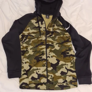 Nike Dri fit, fritidsjacka, kamo, svart, huva. - Nike jacka med hoodie.  Storlek Small. Mycket bra skick, säljes p.g.a för liten för mig. Kamouflage med svarta ärmar och huva två fickor framtill. Rökfritt fläckfritt o djurfritt. 