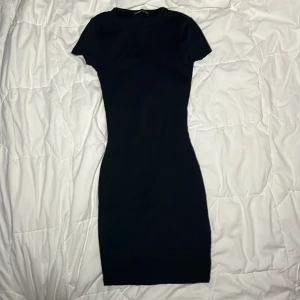 Tight svart kortärmad klänning  - Köpt i fel storlek ungefär 1 år sedan. Aldrig använd. Bra konditon och fin passform. Formas runt kroppen då den är tight. Slutar lite ovanför knäna. 