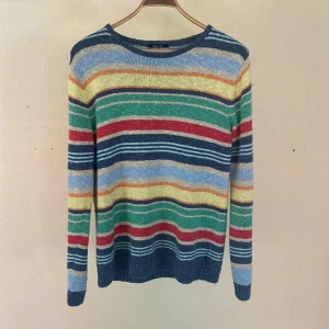 Randig tröja från GANT - En färgglad randig tröja från GANT i storlek M. Tröjan har ett mönster med ränder i blått, grönt, rött, gult och orange. Den är långärmad och tillverkad av bomull och linne, vilket gör den bekväm och tänk andningsbar. -Material: 53% Linen, 47% cotton