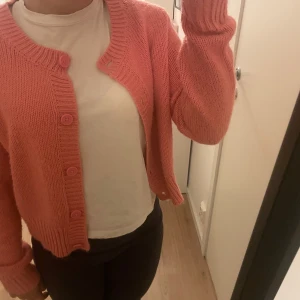 Stickad kofta, korallfärgad - Stickad kofta i en jättefin färg. Perfekt nu till våren! Storlek M