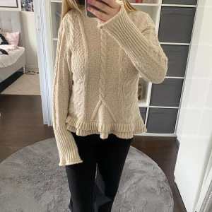 Stickad tröja med volang - Creme vit stickad tröja med volang. Fint skick med fina detaljer.