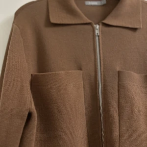 Cardigan med dragkedja - Cardigan med dragkedja framtill och rak, boxig passform, tillverkad i mjuk bomullsmix. CROSS är en stickad overshirt med snygg krage och stora, öppna fickor på bröstet.   Köpt för 599kr. Använd endast 1 gång. 