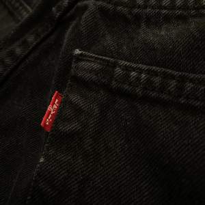 ett par svarta levi’s jeans. lite tecken på användning då byxorna har lite uppslitningar mellan låren men inga hål