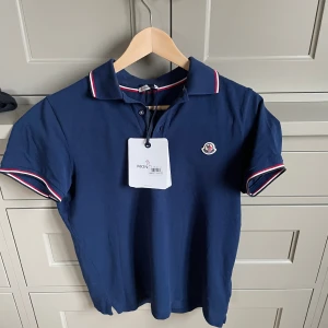 Moncler pike - Säljer nu denna sjukt snygga Moncler piké då den inte kommer till användning. Skulle uppskatta skicket som 9,5\10. Då den är använd 2-3 gånger endast. Kvitto och tags finns, även en fungerande qr-kod. Priset kan diskuteras!