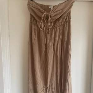 En jättefin beige/brun bandeau klänning från hm, går även att knyta runt halsen🤎 aldrig använd
