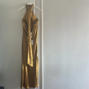 Festklänning  - Festklänning i satin med bar rygg och halterneck modell.