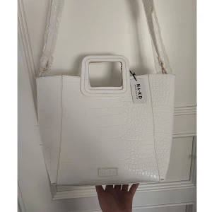 NY vit väska  - Vit lackväska med orm/krokodilfinish, avtagbar axelrem och necessär/pouch. Perfekt skick, ny med prislapp. (Nypris: 549)  41×28 cm 