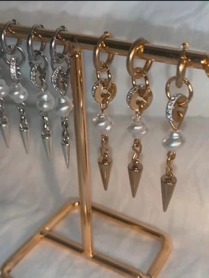 Snygga örhängen med pärlor och spikes - Unika örhängen i både silver och guld med glittrande detaljer, pärlor och coola spikes. Perfekt för dig som vill sticka ut med en edgy och trendig stil. Hängs på örat med rund ring och har en mix av bling och pärlemor.