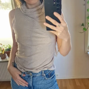 Beige ribbad polotopp - Beige ribbad topp med lång polo, som faller snyggt runt halsen. 95% viskos. Mått: Längd (axel-nederkant)- 52 cm. Inga tecken på användning 🧡 