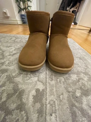 Bruna boots i mocka med platt sula - Säljer ett par bruna boots med rund tå och platt sula som bara har använts ute 1-2 gånger. Skorna är tillverkade i mjuk mocka och har en grov mönstrad yttersula för extra grepp. Insidan är fodrad och de har en enkel, klassisk design utan snörning eller dragkedja. Storleken är 36 men den är lite stor för storleken.💘💘💘