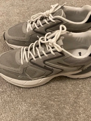 Grå sneakers från Bench i storlek 39 - Snygga grå och vita sneakers från Bench med sportig design. Skorna har bara provats men aldrig använda mer än så. 