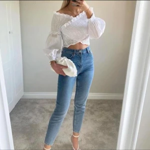 Vit croppad blus med puffärmar - Säljer en vit croppad blus med offshoulder och puffiga långärmar. Toppen har smockad och ribbad överdel med volangdetaljer längs kanterna. Materialet känns lätt och luftigt.