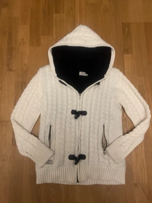  stickad Hollister kofta / cardigan  - Mysig vit stickad kofta från Hollister med svart teddyfoder i huvan. Tröjan har kabelstickat mönster⚪️| Skriv vid funderingar                                   Priset kan självklart diskuteras!!