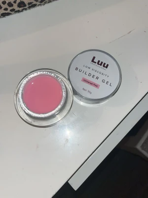 Luu Builder Gel Universal Pink & Super Base Glue - Två burkar från Luu: en low viscosity builder gel i färgen Universal Pink (30g) med en mjuk rosa ton, perfekt för nagelförlängning, och en Super Base Glue (15ml) i svart burk, används som baslim vid nagelbygge. Båda kommer i runda plastburkar med skruvlock. Oanvända typ. Säljer båda för 270