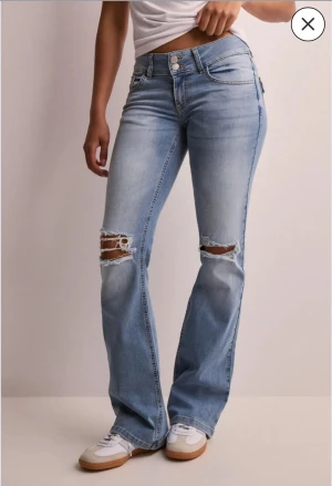 Lågmidjade jeans från nelly  - Lågmidjade ljusblåa jeans med hål, använt nån gång. Från nelly. köptes för 700 kr. 