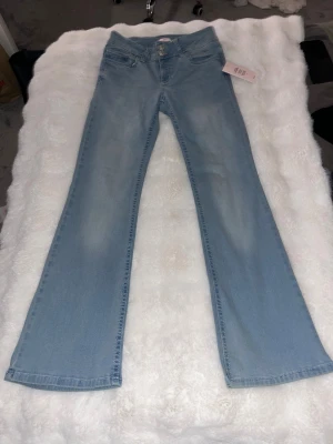 Nelly Low Waist Perfect Bootcut Jeans - Supersnygga virala Nelly bootcut jeans i färg blå, med rosa design på bakfickorna. Storlek 38 i short. Aldrig använda, sitter perfekt!