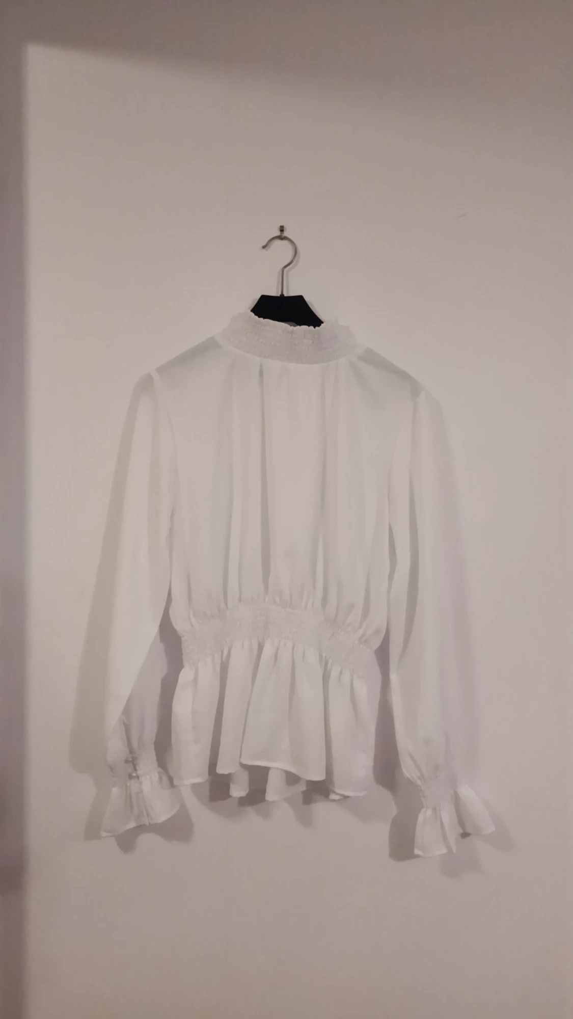 En vit långärmad blus med luftigt tyg och med en halskrage. (Vuxenstorlek)