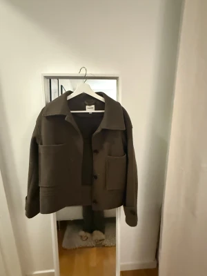 Brun overshirt från Kappahl - Snygg brun overshirt från Kappahl med stora fickor framtill och klassisk krage. Jackan har knäppning med knappar och är tillverkad i ett mjukt ullmaterial. Perfekt för lager-på-lager och har en loose passform som ger en chill vibe.