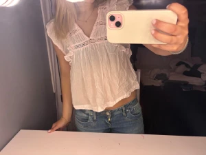 Söt vit blus med volangdetaljer - Säljer en ljus och luftig vit blus med v-ringning och volangdetaljer vid axlarna. Blusen har spetsinslag och är ärmlös med en loose passform. Perfekt för sommarens alla tillfällen, superfin till jeans eller kjol🍒🍒❤️❤️❤️